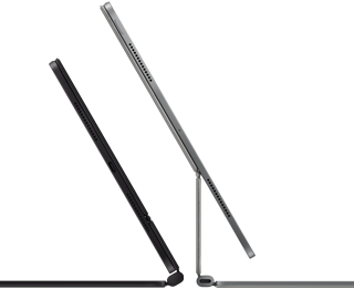 Two iPad Pro devices attached to Magic Keyboard, side exterior, thin profile, space black colour with speakers and USB-C port, tilted half open, silver colour, open, tilted back showing the keyboard’s floating cantilevered design, speakers and microphone