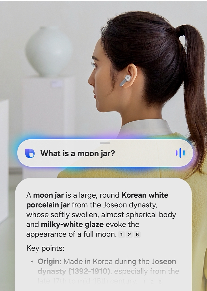 A rearview shot of a woman using a single, white Galaxy Buds4 Pro. Nearby, a text bubble asking AI, 'What is a moon jar?' Below the text bubble is a separate bubble with the response 'A moon jar is a large, round Korean white porcelain jar from the Joseon dynasty, whose softly swollen, almost spherical body and milky-white glaze evoke the appearance of a full moon.' Below is a list of the key points of a moon jar.